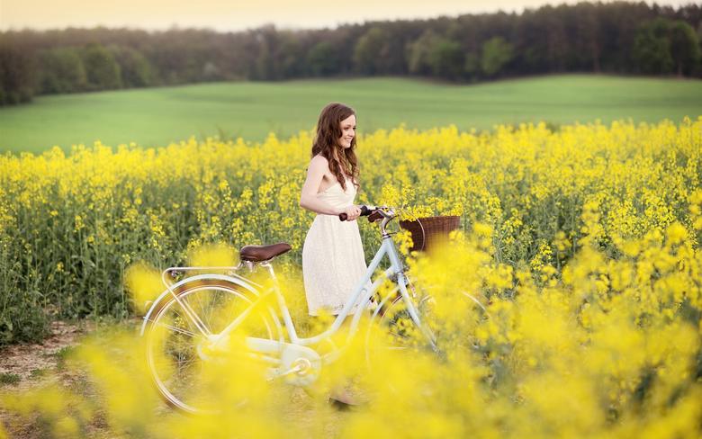 Девушка с велосипедом в желтом поле